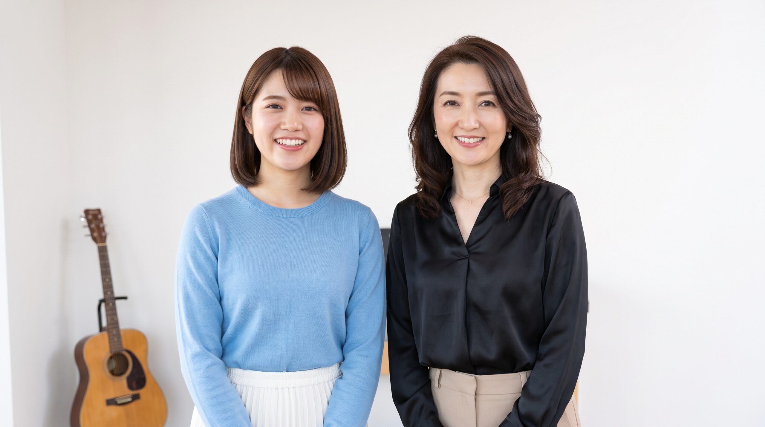 白い壁とギターの前で、並んで笑顔を見せる生徒と講師